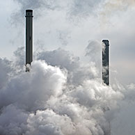 Pollution from petrochemical industry showing chimney encompassed with smoke, Antwerp harbour, Belgium